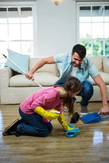 Daughter helping father to clean floor at home